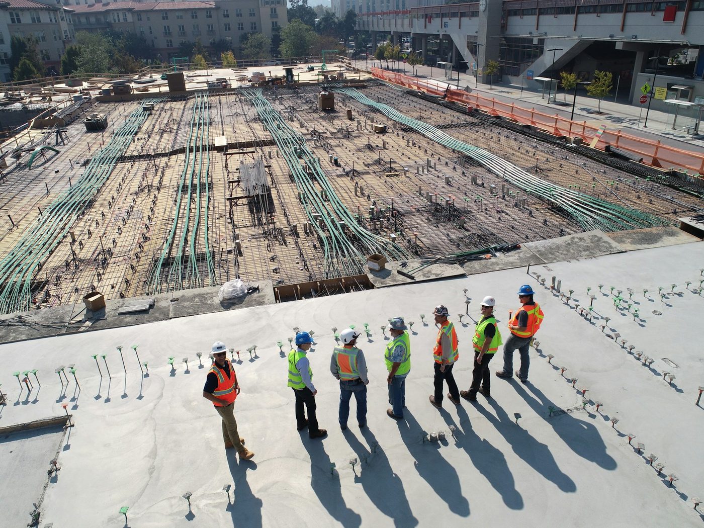 A construction crew in hard hats and hi-vis vests on an active job site