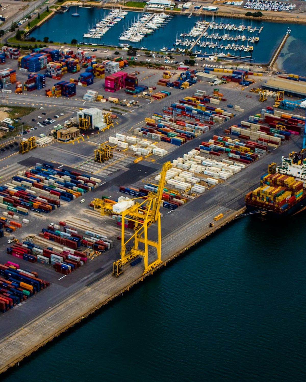 Aerial view of a container port terminal with gantry cranes and a cargo ship
